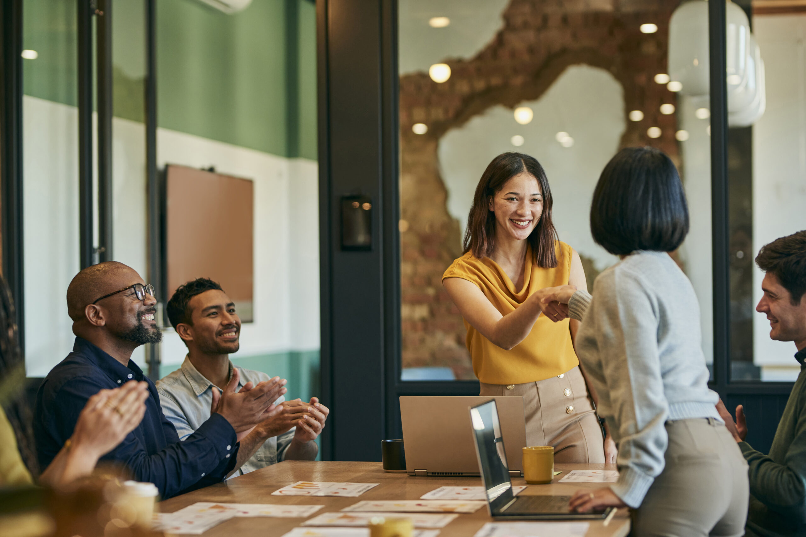Cheerful businesswomen shaking hands at client meeting in boardroom